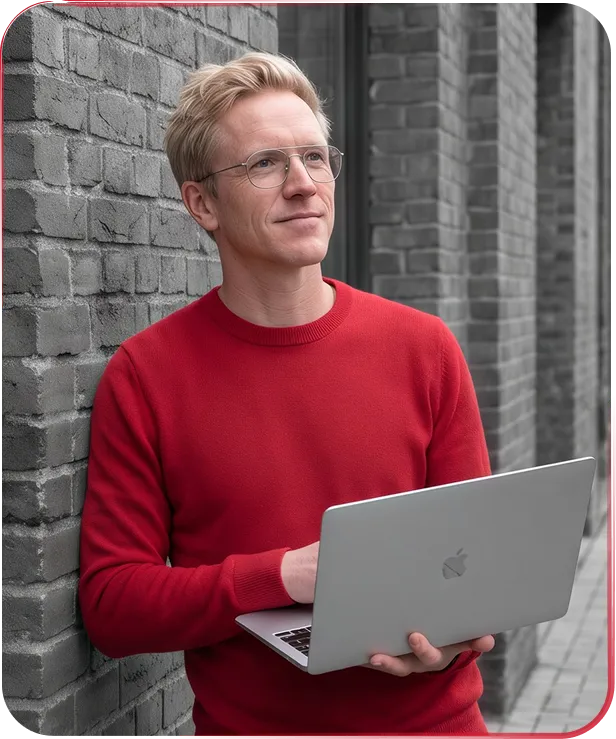 Consultant in a red jumper with a laptop against a brick wall