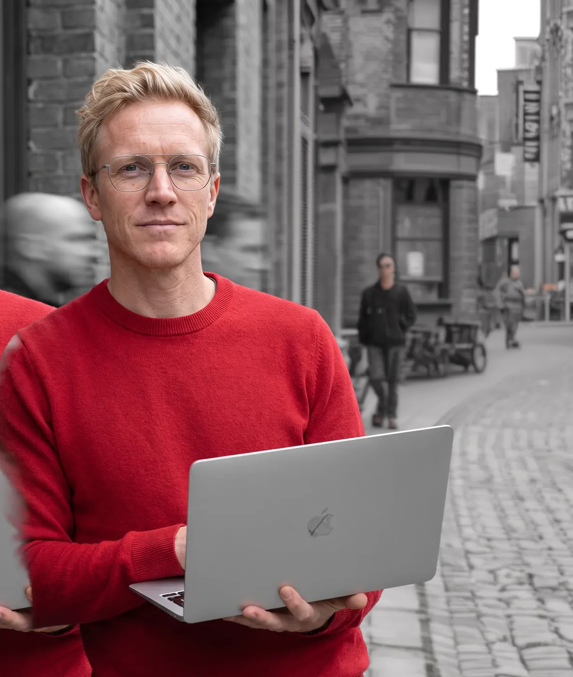 Consultant in a red jumper with a laptop on a city street