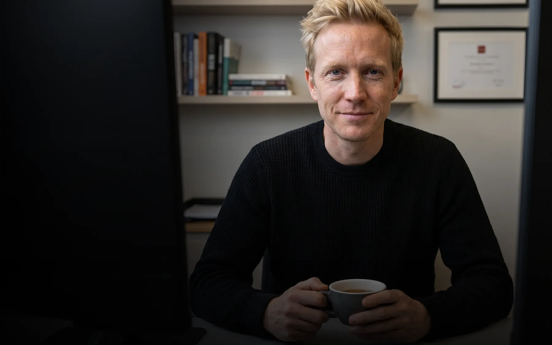 Consultant seated at his desk with a cup of coffee, ready for a call